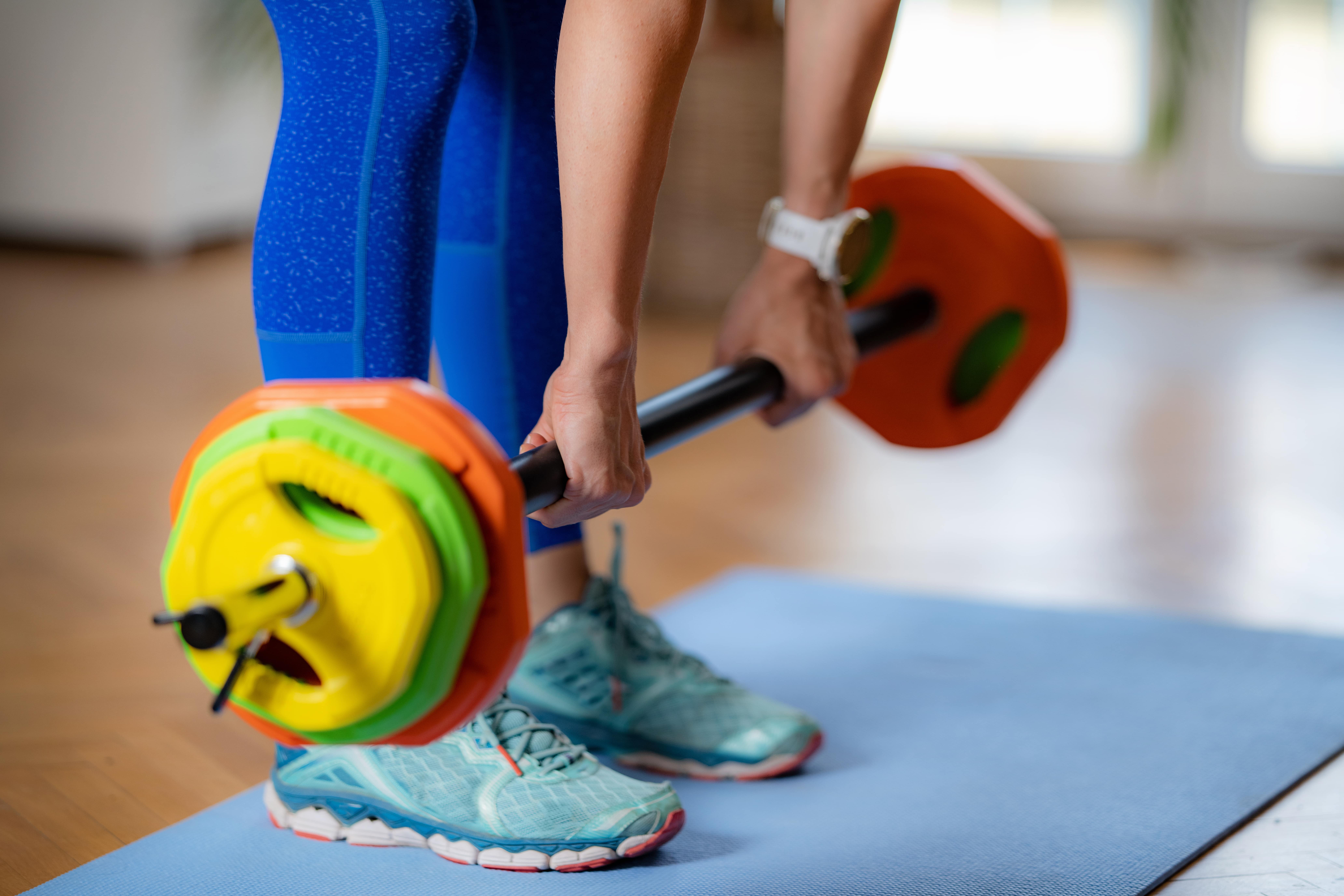 exercising-at-home-woman-using-barbell-bar-with-w-2024-10-20-10-43-38-utc-min